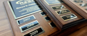 3 Best Practices Plaques stacked on top of each other showing the years HWP has been designated a Best Practices Agency. The plaques are brown with black year markers on them.